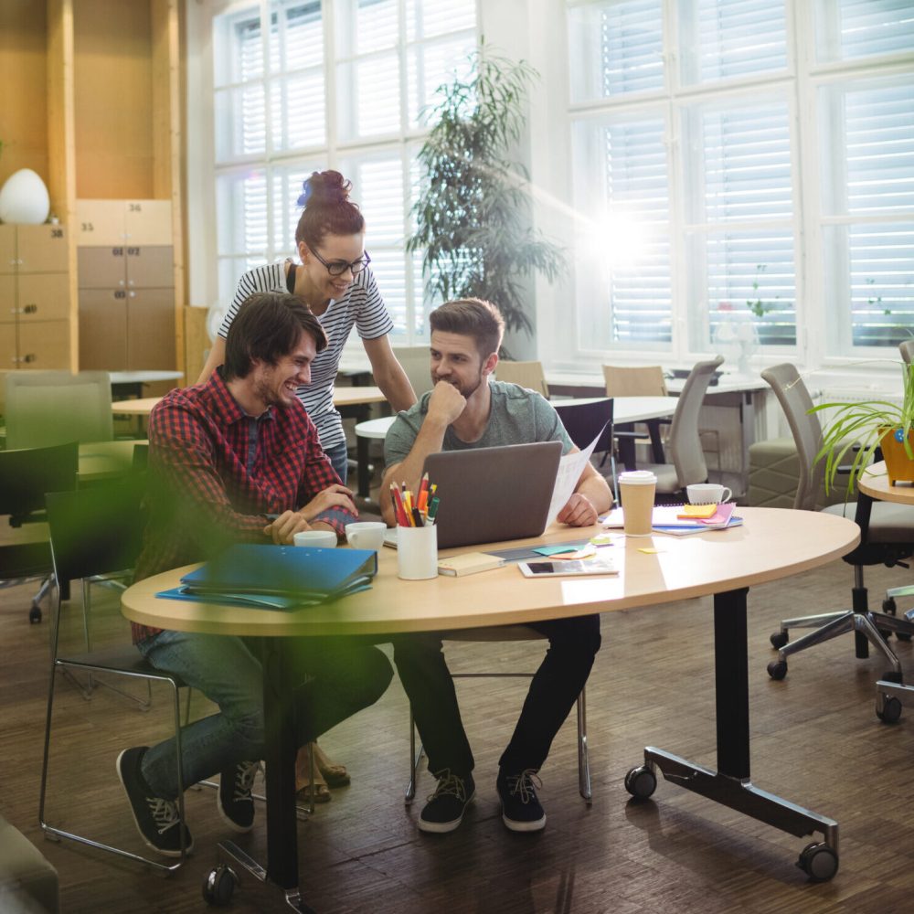 Group of business executives discussing over laptop at their desk in the office